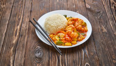 Portakal soslu tatlı ve ekşi tavuk, sebze, pirinç ve ahşap zemin üzerinde çubuklar, kopyalama alanı olan Asya yemekleri konsepti.