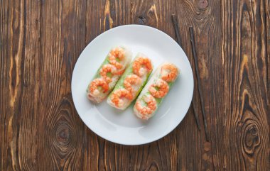 Koyu ahşap arka planda karidesli Asya yemeği böreği. Pirinç dilimli börekler ve çubuklar. Metin için üst görünüm alanı