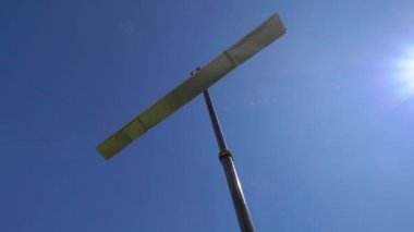 Kancalı bir vinç ve halatlarda asılı bir metal profil, güneşli mavi gökyüzü ile alçak açı, inşaat malzemelerini taşımak için endüstriyel vinç kullanılıyor.