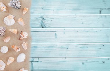 Birçok beyaz, bej renkli egzotik deniz kabuğunun bileşimi farklı şekillerde ve kumun üzerine yazılmış. Mavi ahşap arka planda deniz reklamcılığı konsepti. Düz yat, üst görünüm, kapat, boşluğu kopyala