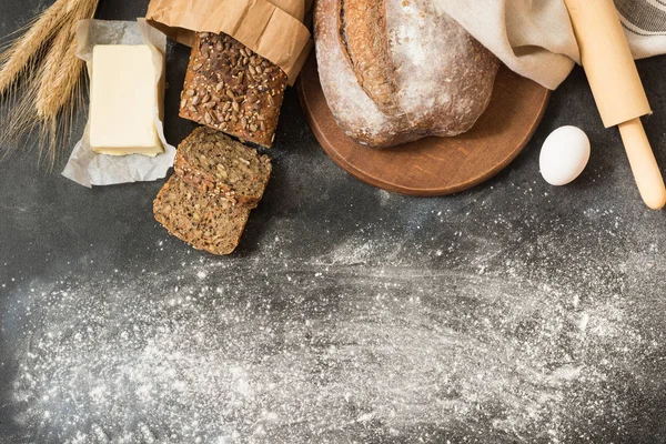 Çeşitli ev yapımı çavdar ekmeği ve buğday siyah taş masada. Ekmek pişirme için malzemeler. Metin için yer. Üstten görünüm.