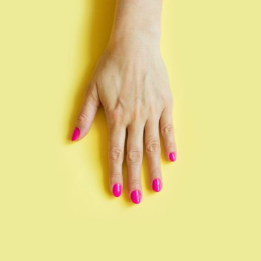 Sarı zemin üzerine pembe tırnak tek kadın eliyle trendy tarzı. Kavramı.