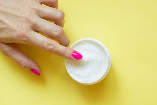 Female hand with pink nail on yellow. Concept.