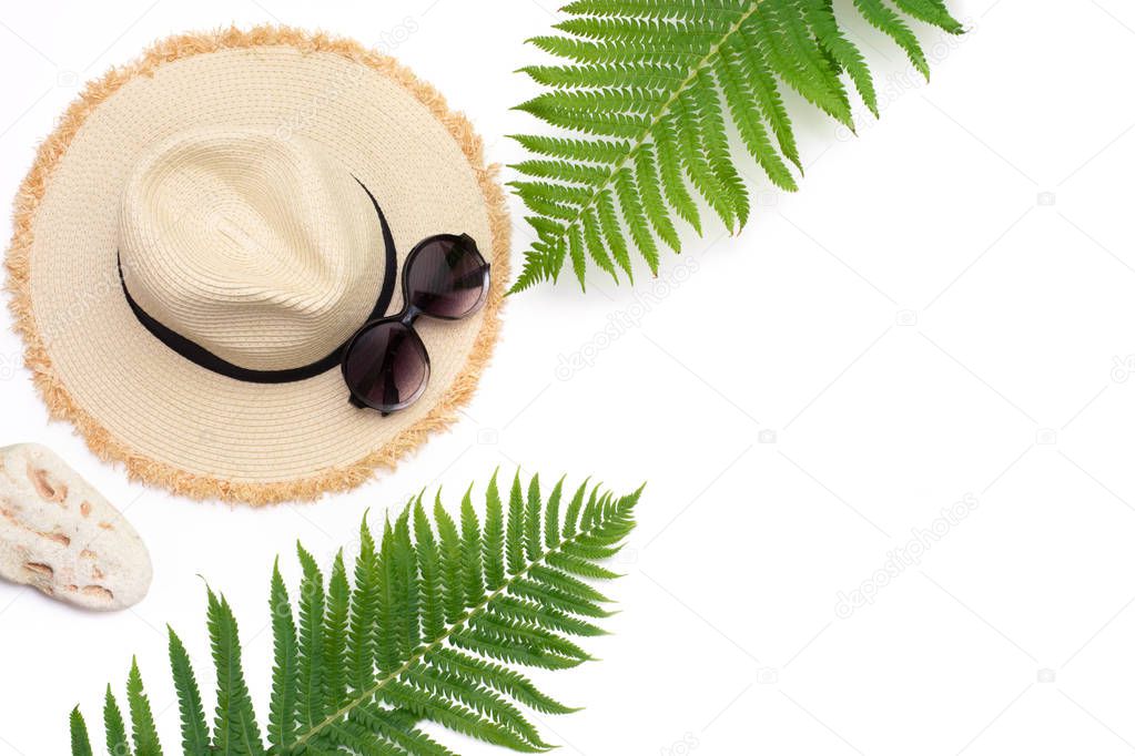 Tropical vacation. Straw beach sunhat, sunglasses, leaf of fern on white background. Top view with copy space. Summer concept.
