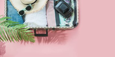 Pastel pembe gezisi için kadın giysileri ile açık bavul. Üstten görünüm kopya alanı ile. Yaz konsepti seyahat.