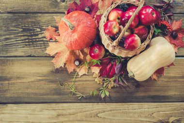 Sonbaharda hasat, kabak, elma sepeti ahşap tahta üzerinde renkli sonbahar yaprakları. Sonbahar natürmort, vintage tarzı. Üstten görünüm. Kopya alanı.