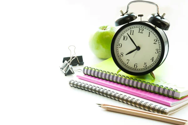 Coloridos útiles escolares, libro y despertador en blanco. De cerca. Regreso a la escuela . — Foto de Stock