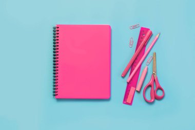 Pembe kız gibi okul malzemeleri, defter ve kalemler punchy mavi zemin üzerine. Üstten görünüm, düz yatıyordu. Kopya alanı.