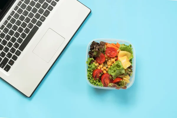 Healthy business lunch in office, salad for snack on blue. Top view with copy space. Concept proper nutrition. Office lunch. Take away lunchbox.