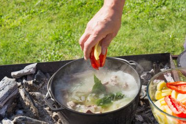 Shurpa çorba büyük bir demir döküm kazan açık. Zam için yaz yiyecek. Yemek. Mens elini çorba için malzemeler.