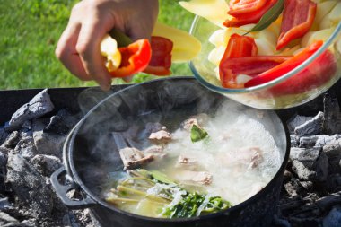 Shurpa çorba büyük bir demir döküm kazan açık. Zam için yaz yiyecek. Yemek. Mens elini çorba için malzemeler.