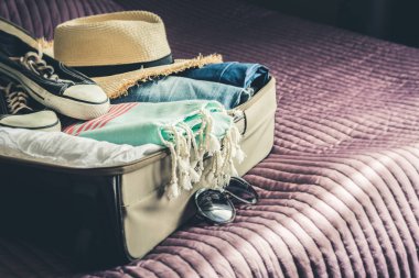 Açık bavul yatakta plaj tatil için kadın giysileri ile. Ambalaj şeyler.