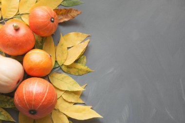 Turuncu kabak ile gri ahşap masa üzerinde sarı yapraklar sonbaharda hasat. Sonbahar çerçeve.