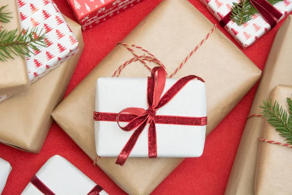 Coffret cadeau de Noël enveloppé dans du papier d'ornement et un ruban de corde rouge décoratif sur la surface rouge. Loisir créatif, vue de dessus. Préparez-vous à Noël . — Photo