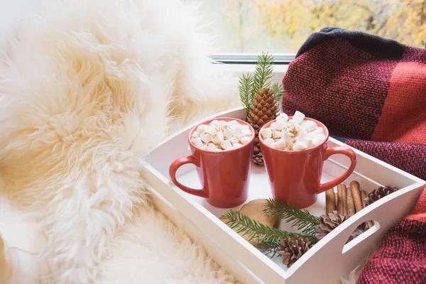Zwei rote Tassen heiße Schokolade mit Eibisch auf weißem Fensterbrett mit Pelzhaut zum Ausruhen. Urlaub. Weihnachtsmorgen. — Stockfoto