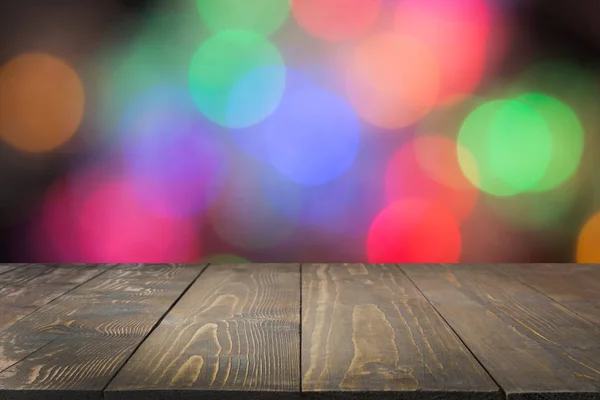 Wooden dark tabletop and blurred colorful bokeh. Christmas background . — Stock Photo, Image