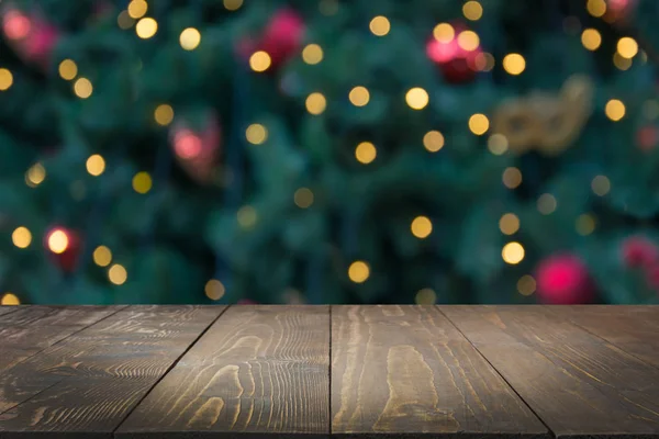 Dřevěné stolní tmavé a rozmazané vánoční strom bokeh. Vánoční pozadí pro zobrazení vašich výrobků. — Stock fotografie