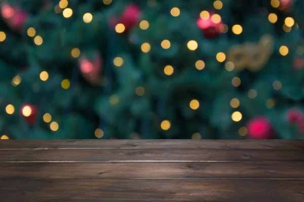 Wooden dark tabletop and blurred christmas tree bokeh. Xmas background for display your products. — Stock Photo, Image