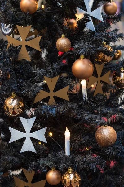 Christmas tree with gothic dark decor, golden balls, candles on dark in interiors. Xmas.Close up.