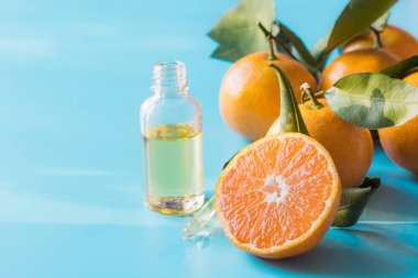 Pastel mavi arka plan üzerinde cam şişe portakal mandarin esansiyel yağı. Spa ve sağlıklı yaşam konsepti.