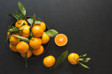 Taze mandalina siyah kase yaprakları ile. Sağlıklı beslenme kavramı. Uzay kopyalayın. Üstten görünüm.