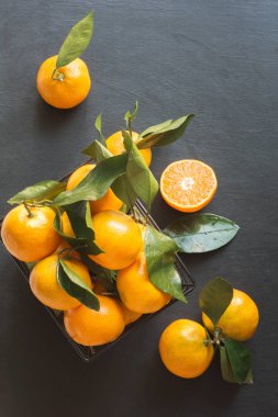 Taze mandalina ile modern kase yapraklarda siyah. Sağlıklı beslenme kavramı. Uzay kopyalayın. Üstten görünüm.