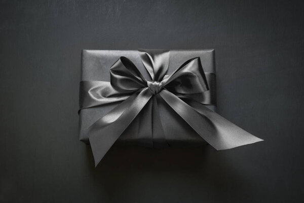 Gift box wrapped in black paper with black ribbon. Top view.