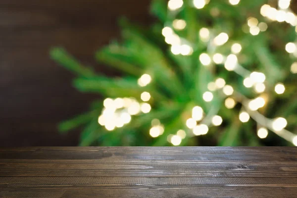 Hölzerne dunkle Tischplatte und verschwommenes Weihnachtsbaum-Bokeh. Weihnachten Hintergrund für die Anzeige Ihrer Produkte. — Stockfoto