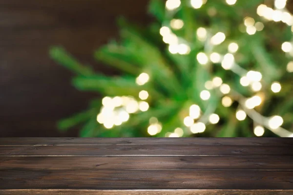 Dřevěné stolní tmavé a rozmazané vánoční strom bokeh. Vánoční pozadí pro zobrazení vašich výrobků. — Stock fotografie