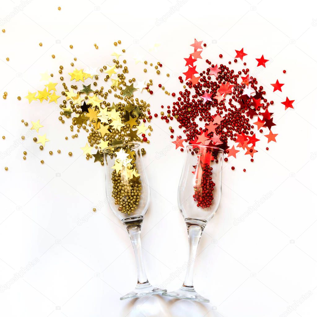 Golden and red confetti poured out glasses of champagne. Top view. Christmas party. Magic night.