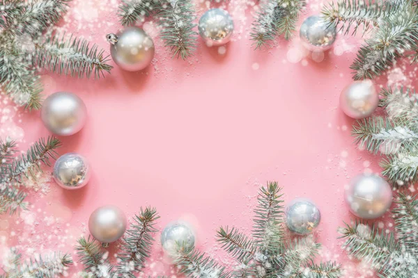 Marco de Navidad hecho de ramas de abeto, decoraciones blancas nevadas, bolas blancas en la mesa rosa. Fondo de Navidad. Acostado. Vista superior con espacio de copia —  Fotos de Stock