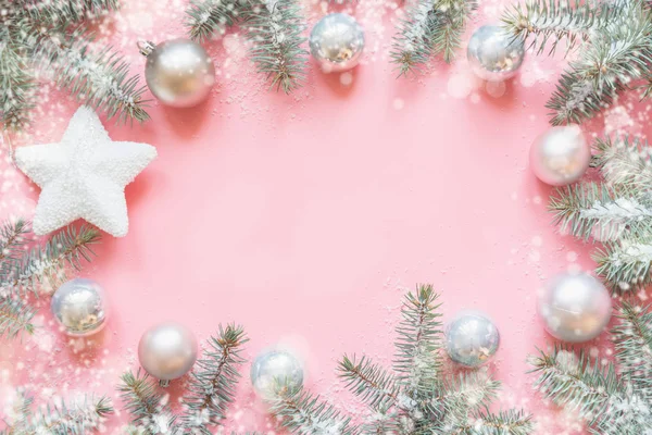 圣诞框架由冷杉树枝, 雪白的装饰, 白色的星星, 粉红色的桌子上的球。圣诞节背景。平躺着。带复制空间的顶视图 — 图库照片