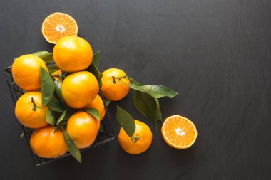 Taze mandalina siyah kase yaprakları ile. Sağlıklı beslenme kavramı. Uzay kopyalayın. Üstten görünüm.