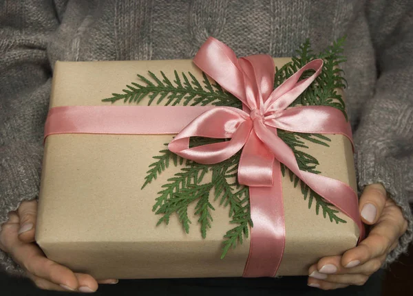 Frauenhände halten Weihnachts- oder Neujahrsgeschenkbox mit rosa Schleife. Gedämpftes Bild. — Stockfoto