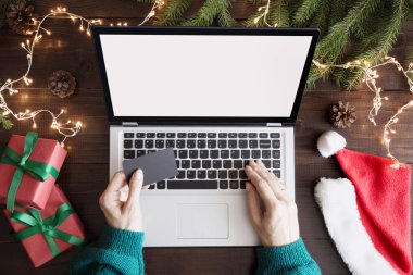 Noel satış. Laptop yanında kredi kartı ile alışveriş kadın. Metin üstünde perde için yer. Üstten görünüm klavye, insan eli, ahşap masa üzerinde Noel hediyesi. Tatil kavramı