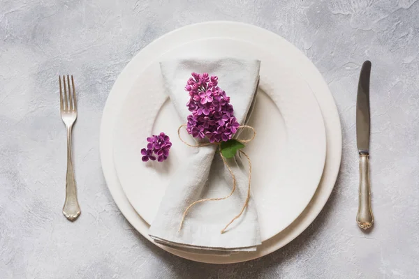 Frühlingshaft elegante Tischdekoration mit violettem Flieder, Besteck auf Vintage-Tisch. Blick von oben. — Stockfoto