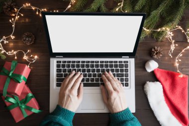 Noel satış. Yazma ve laptop yanında araştırıcı kadın. Metin üstünde perde için yer. Üstten görünüm klavye, insan eli, ahşap tahta üzerinde Noel hediyesi. Tatil kavramı