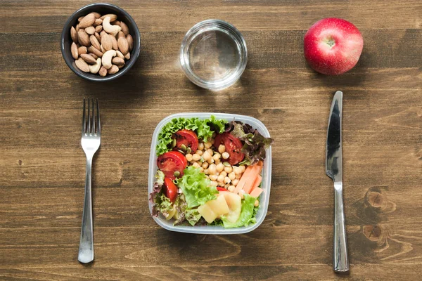 Vegetables salad for office lunch in container on wooden table. Concept healhy nutrition. Lunchbox.