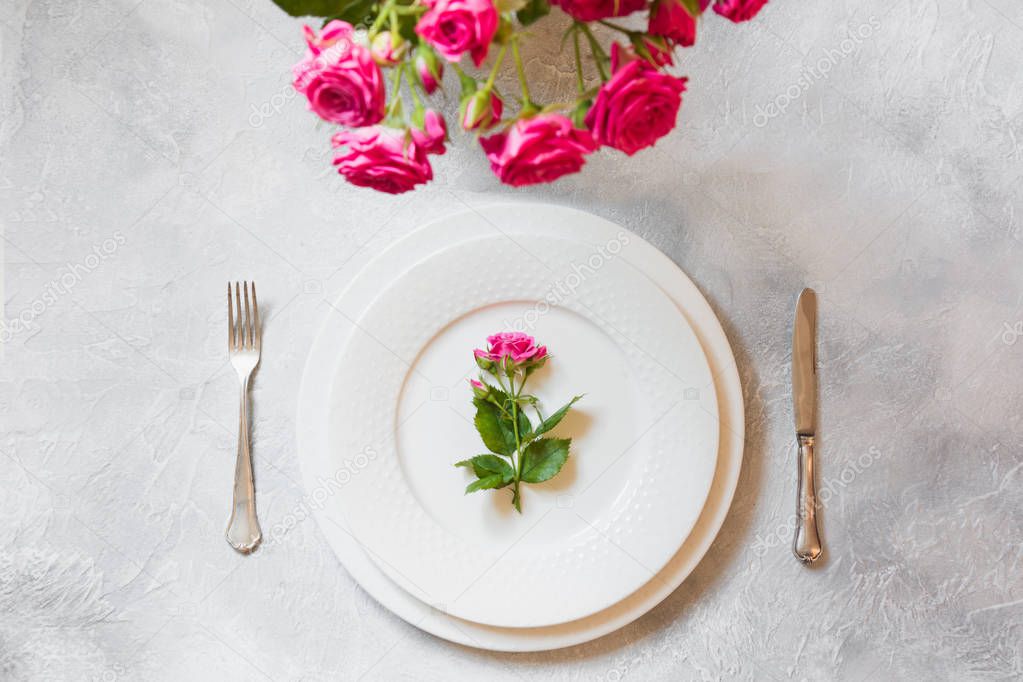 Romantic table setting with bouquet of pink roses, and decorations. Top view. Selective focus.