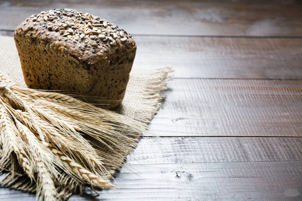 Hoja de pan de centeno fitness con espigas de trigo, en rodajas en la tabla de cortar. De cerca. . —  Fotos de Stock