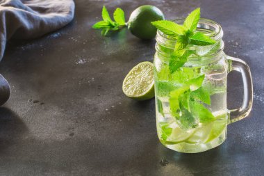 Mojito kokteyl limon ve nane, mason kavanoza siyah masaya süsleyin. Yakın çekim. Metin için yer kopyalayın.