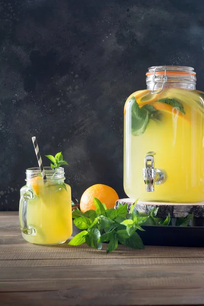 Summer healthy detox drink. Lemonade with orange, lemon and mint in mason jar on black and wooden board. Copy space.