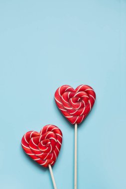 Sevgililer günü kartı. Kalp üzerinde mavi arka plan olarak iki lolipop şeker. Komik kavramı.