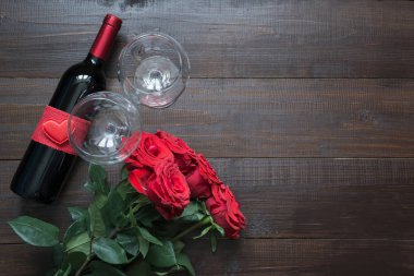 Sevgililer günü tebrik kartı romantik kırmızı gül ve ahşap tahta üzerinde şarap şişesi. Metin için yer ile üstten görünüm.