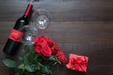 Romantik kırmızı gül, şarap şişesi, kalp ve ahşap masa üzerinde kırmızı hediye kutusu ile Sevgililer kartı. Üstten görünüm metin için yer ile. Düz yatıyordu.