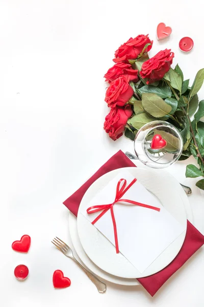 Valentine\'s day or birthday romantic dinner. Elegance table setting with champagne, gift box and bouquet red roses.