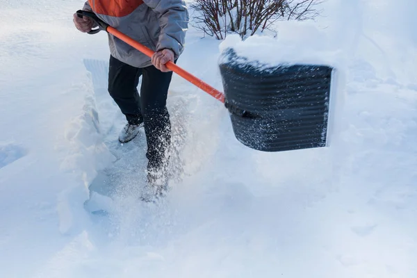 Snow removal. Man clearing snow by shovel after snowfall. Outdoors.