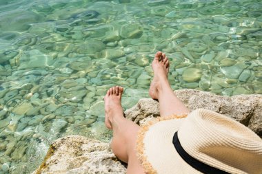 Kadın bacakları taş ile deniz kenarında. Temiz su. Yaz tatili. Yakın çekim.