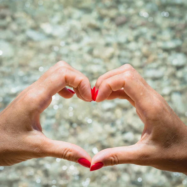 Mano Femenina Con Clavo Rojo Forma Corazón Playa Como Fondo — Foto de Stock