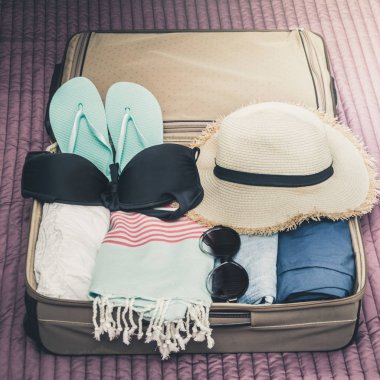 Açık bavul gezi tatil yatakta kadın plaj kıyafeti ile. Ambalaj şeyler.